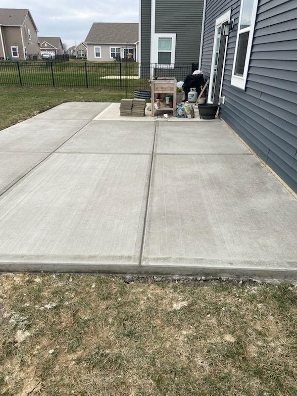 Curved concrete patio beside backyard landscaping
