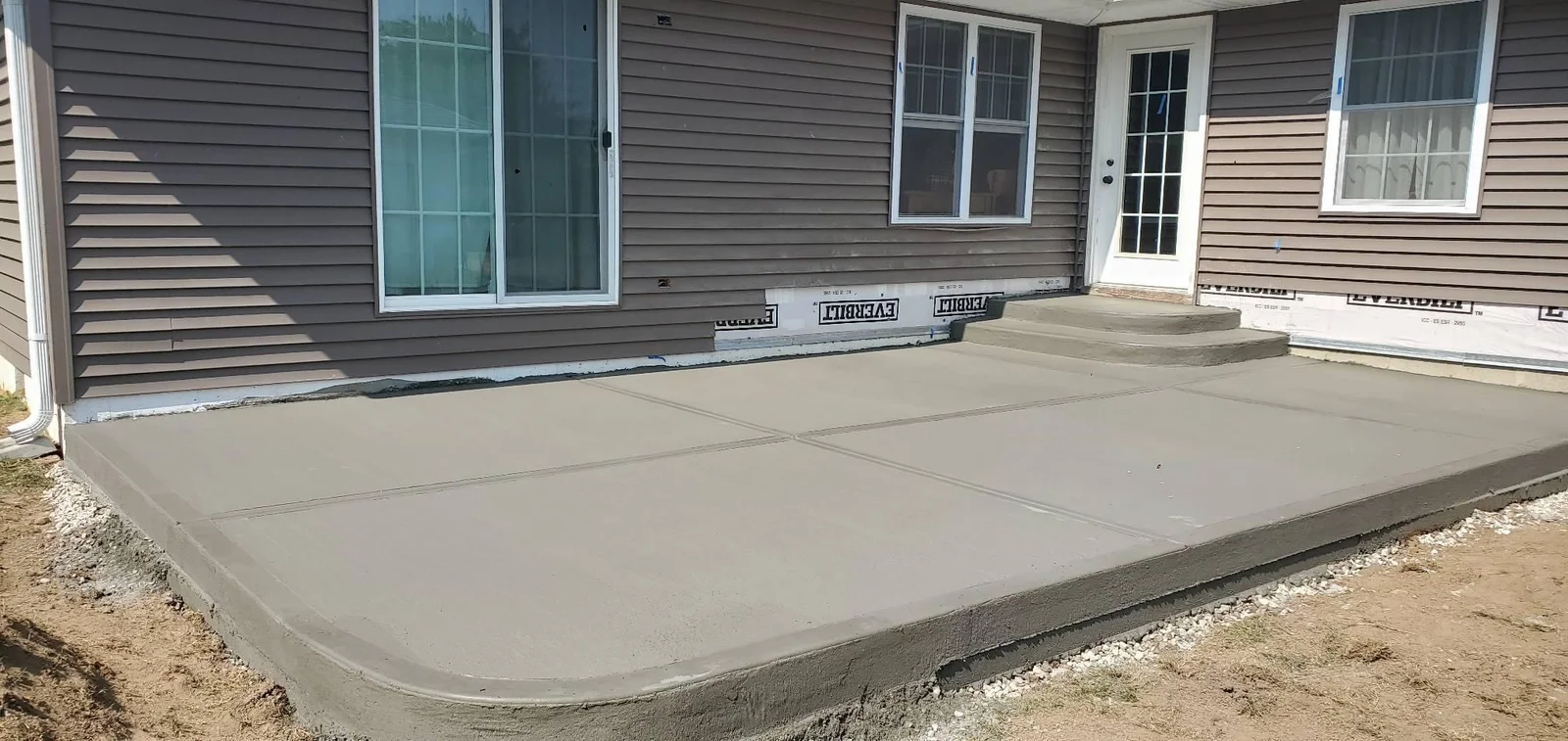New broom-finish concrete patio with picture-frame borders and concrete steps