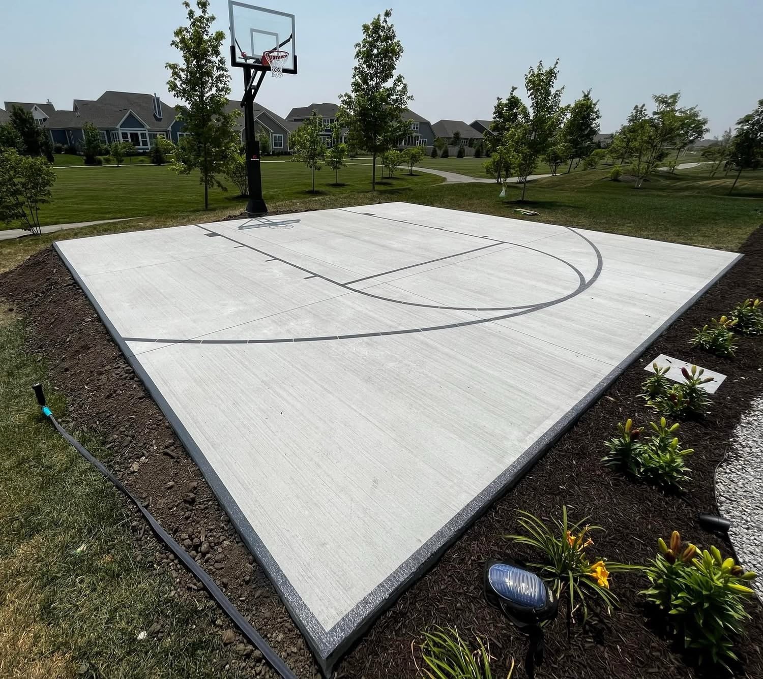 Residential backyard basketball court with a concrete playing surface