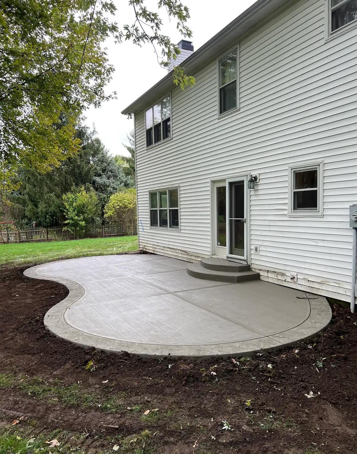Curved concrete patio beside backyard landscaping